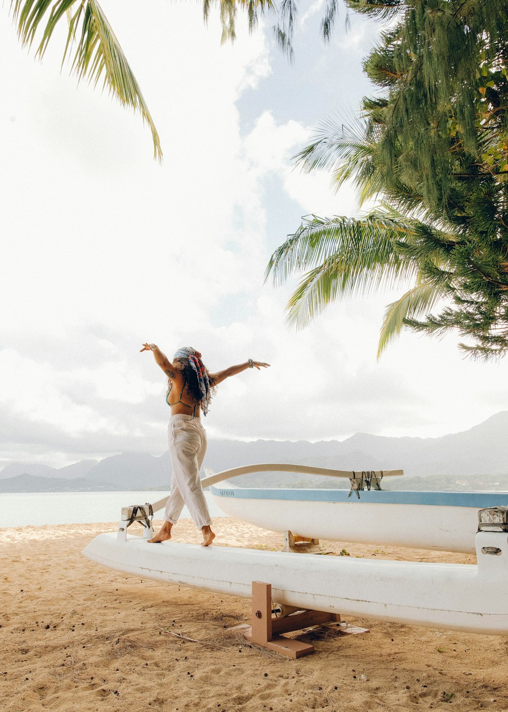 woman in white shirt and white pants standing on beach shore during daytime