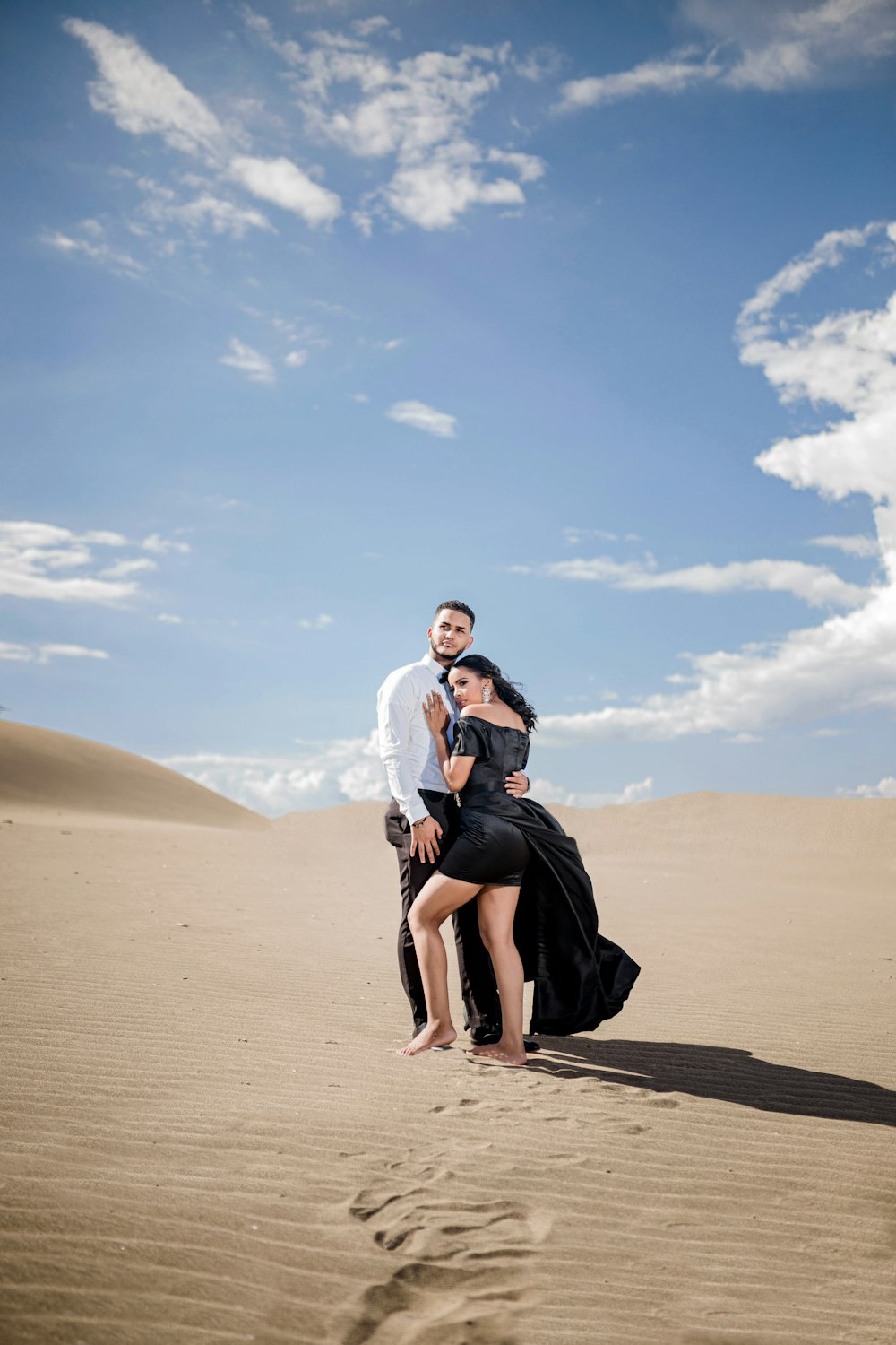 woman in black dress sitting on brown sand under blue sky during daytime