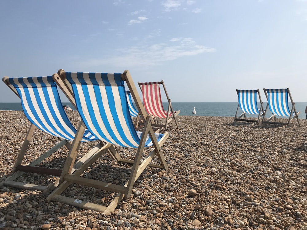 blue and white striped folding chairs on beach during daytime