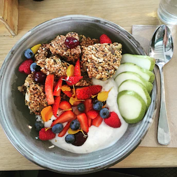A bowl of creamy yogurt topped with colorful fresh berries and crunchy granola