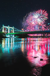 fireworks display over bridge over river during nighttime