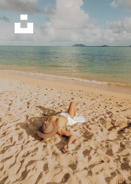 Woman in white bikini sitting on beach shore during daytime photo