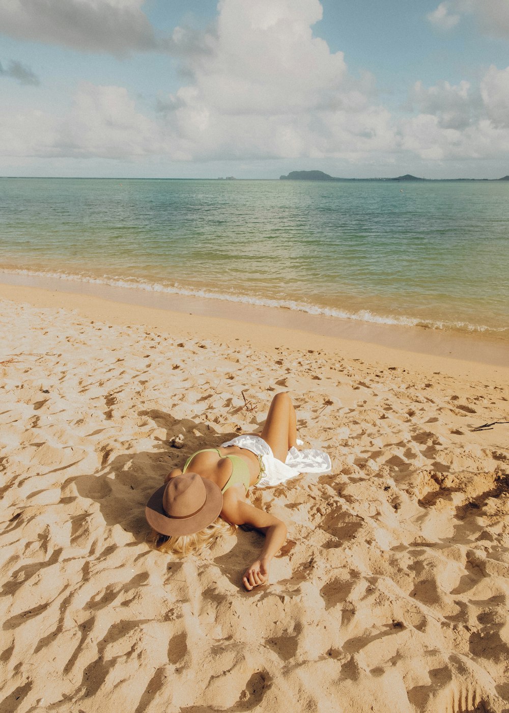 woman in white bikini sitting on beach shore during daytime