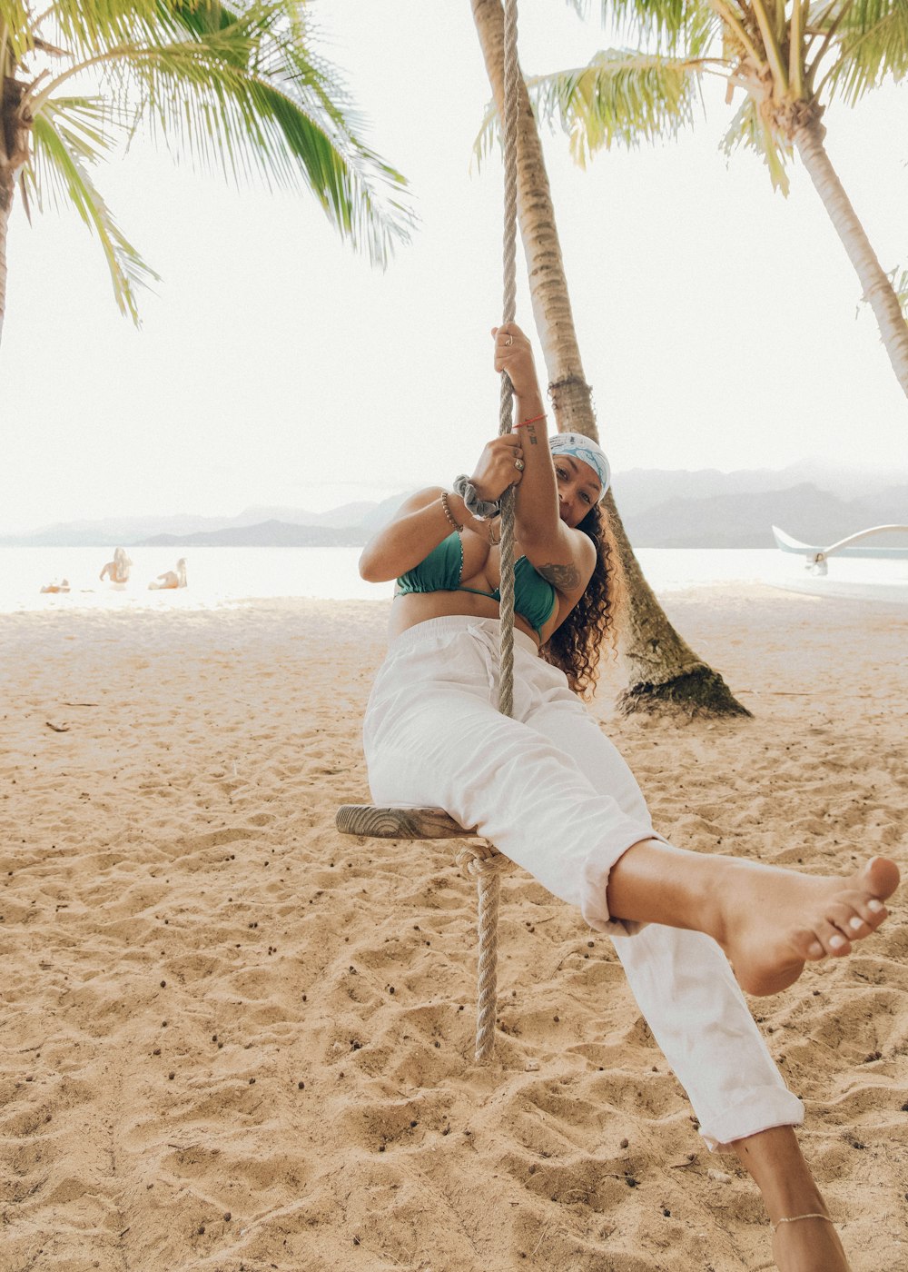woman in white tank top and white pants sitting on hammock