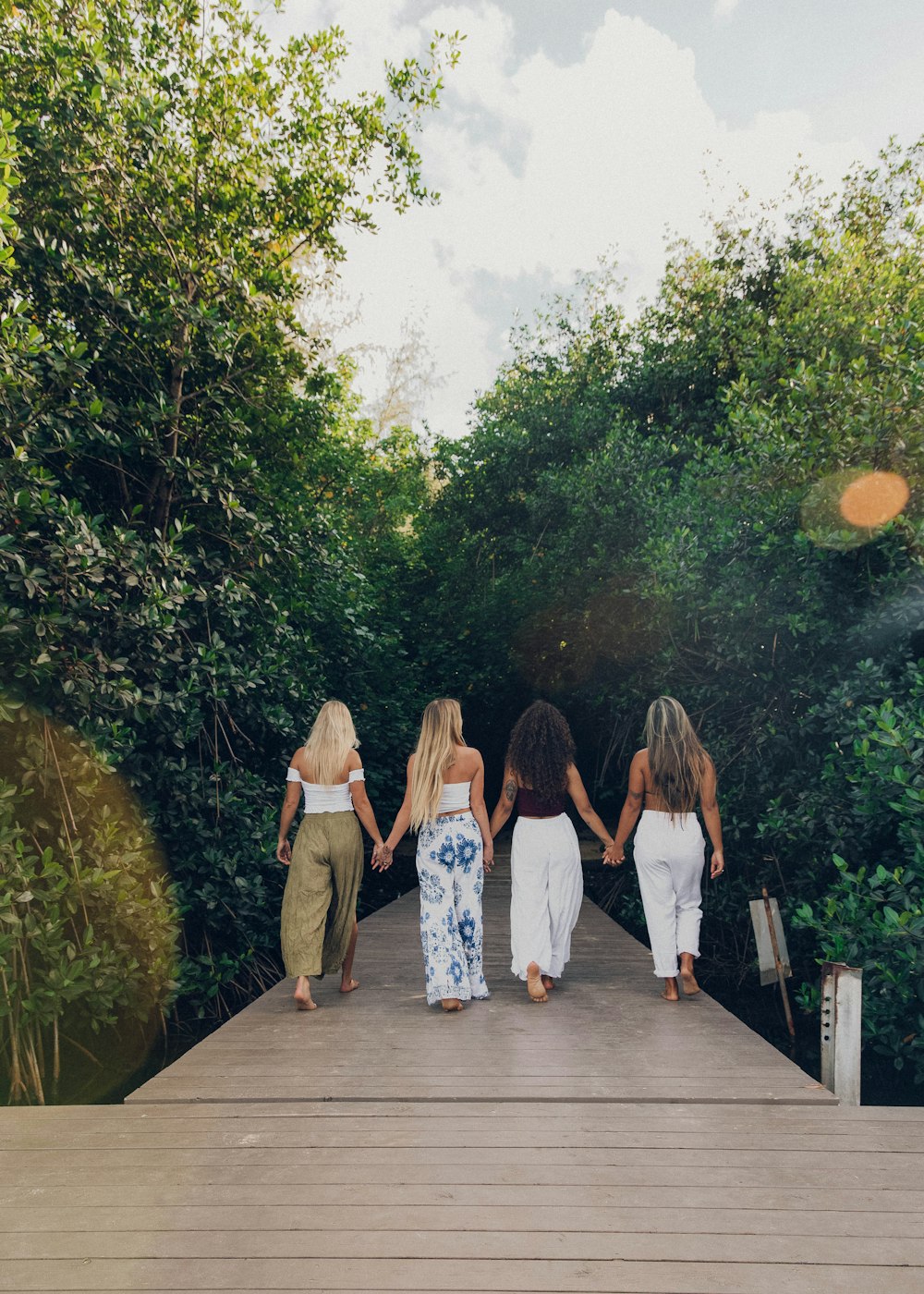 3 women standing on wooden bridge