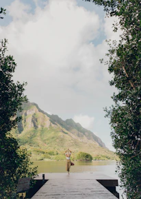 person standing on green grass field near body of water during daytime