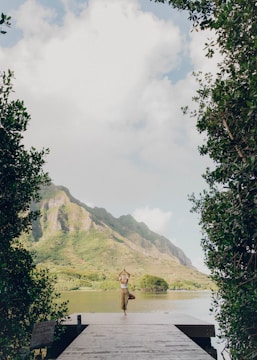 person standing on green grass field near body of water during daytime