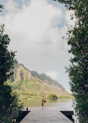 person standing on green grass field near body of water during daytime