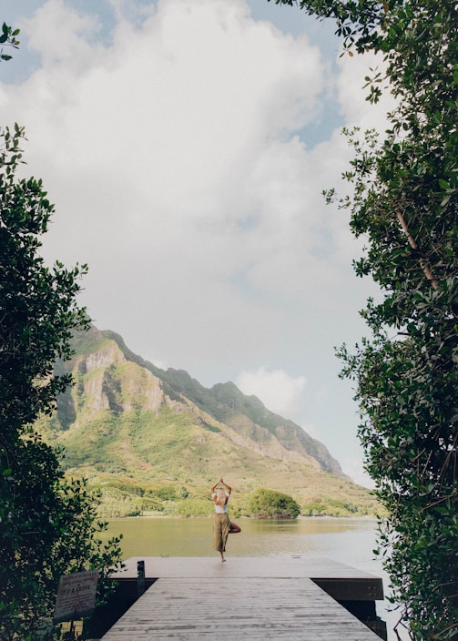 person standing on green grass field near body of water during daytime