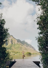 person standing on green grass field near body of water during daytime