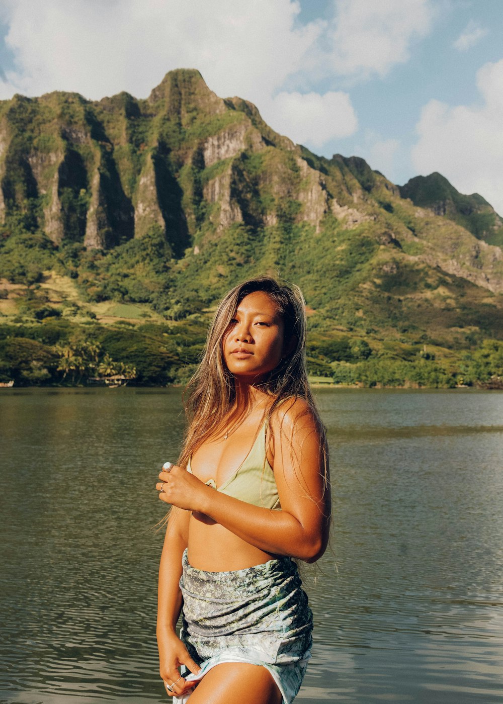 woman in white and black floral spaghetti strap top standing near lake during daytime