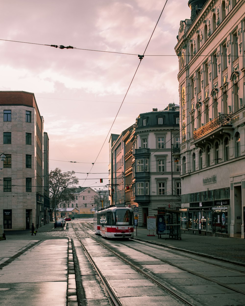 tram rosso e bianco sulla strada vicino all'edificio in cemento marrone durante il giorno