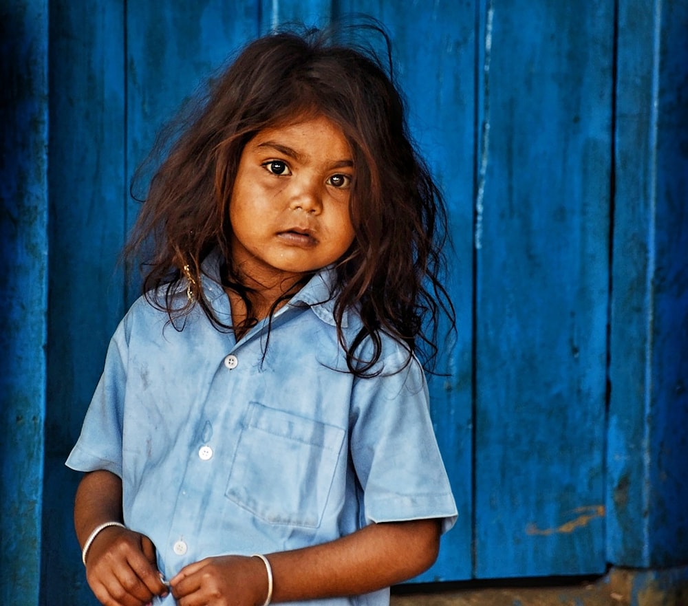 woman in white button up shirt leaning on blue wall