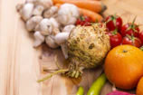A colorful assortment of fresh vegetables and roots displayed on a green and orange cloth backdrop.