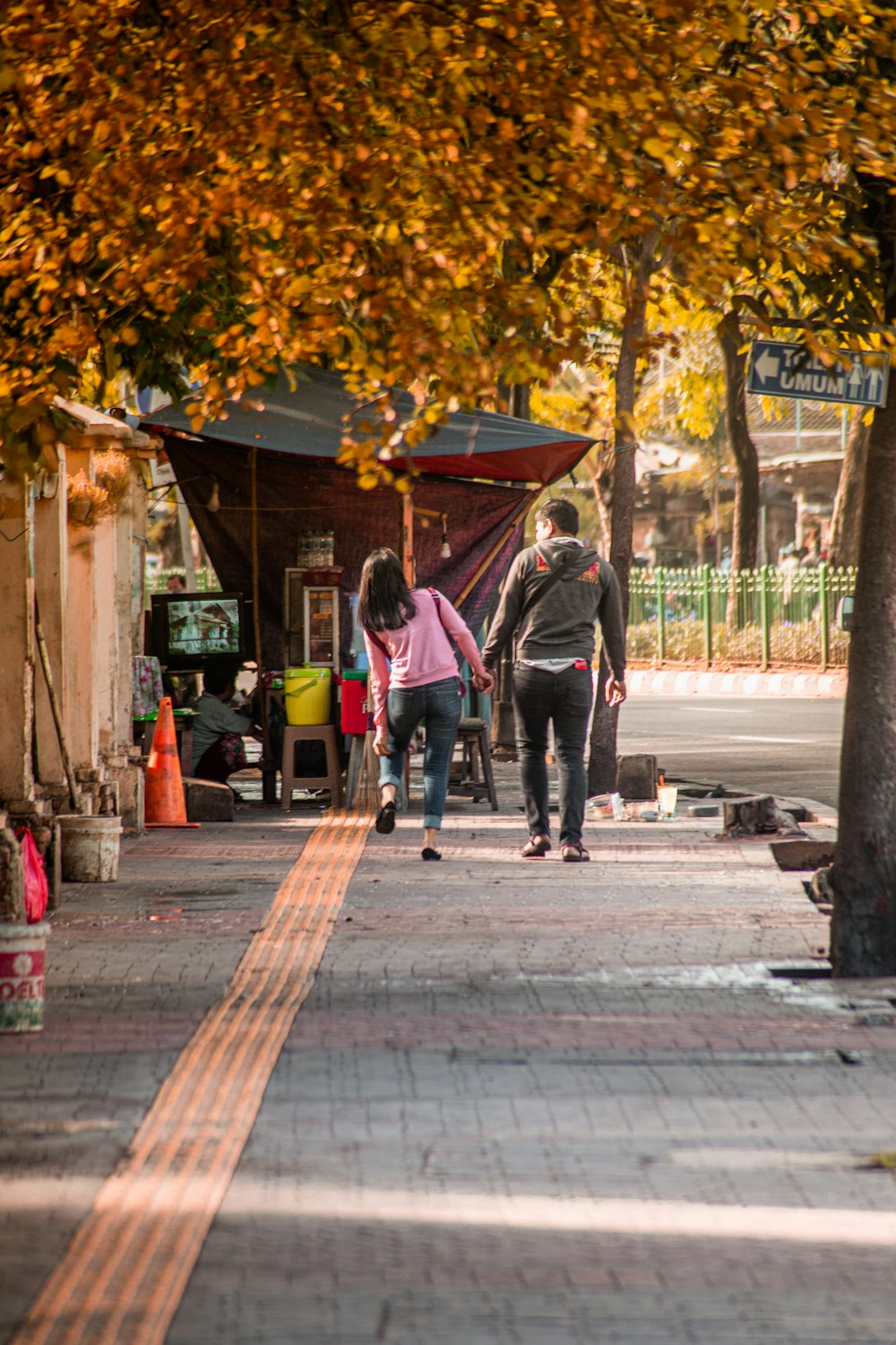 man in black jacket walking on sidewalk during daytime