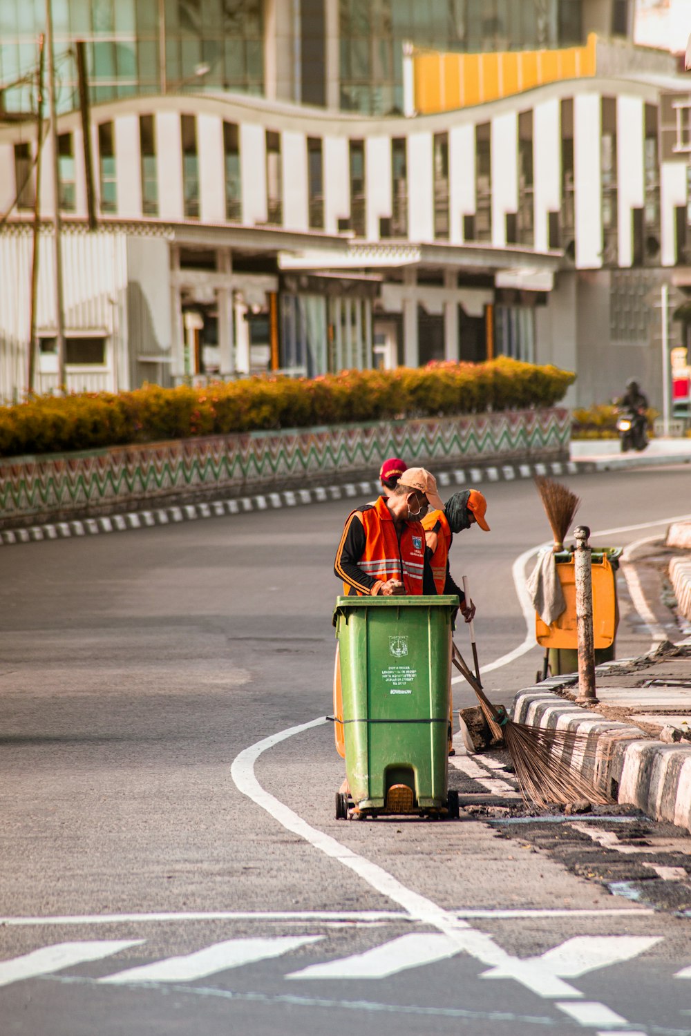 man in red jacket sitting on green trash bin