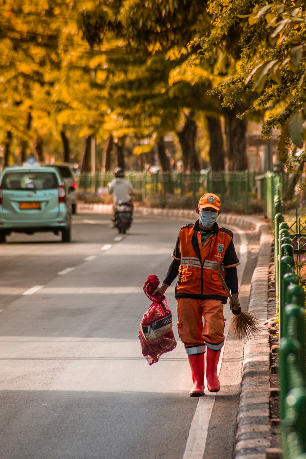 man in red and black jacket walking on sidewalk during daytime