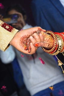 person holding gold and red beaded necklace