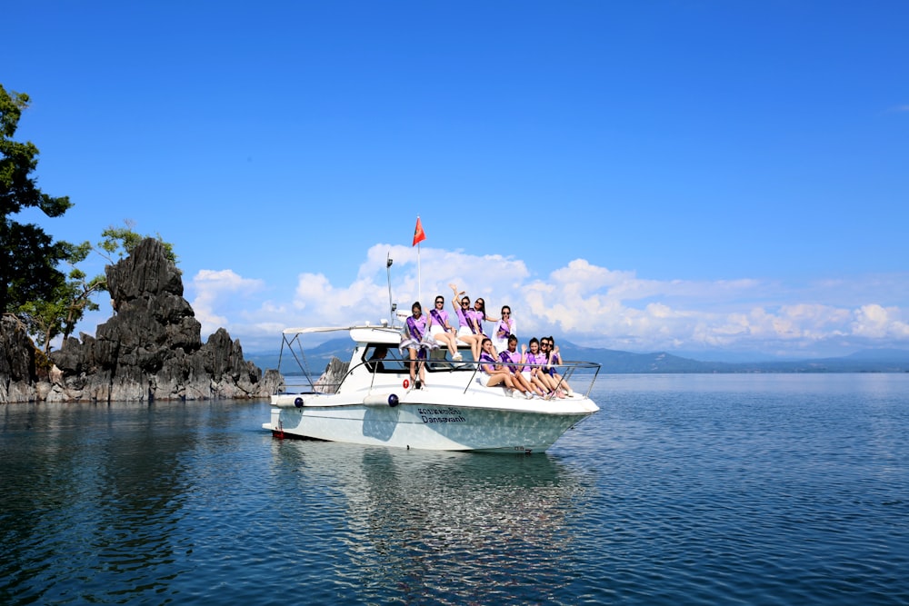 people riding on white boat on sea during daytime