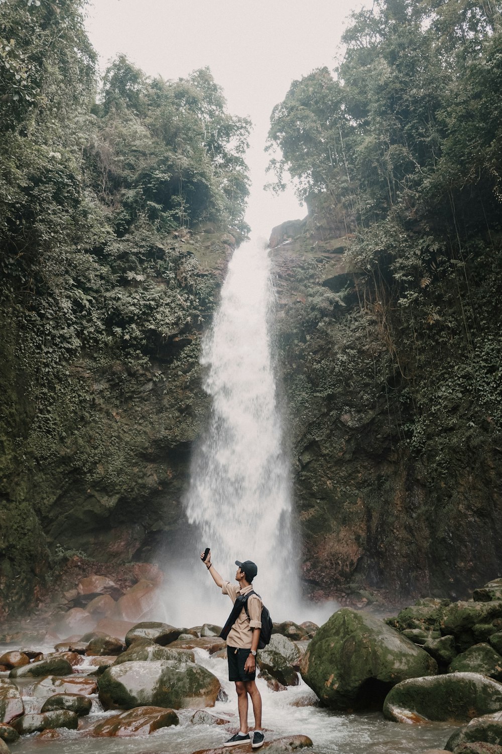 Un homme debout devant une cascade