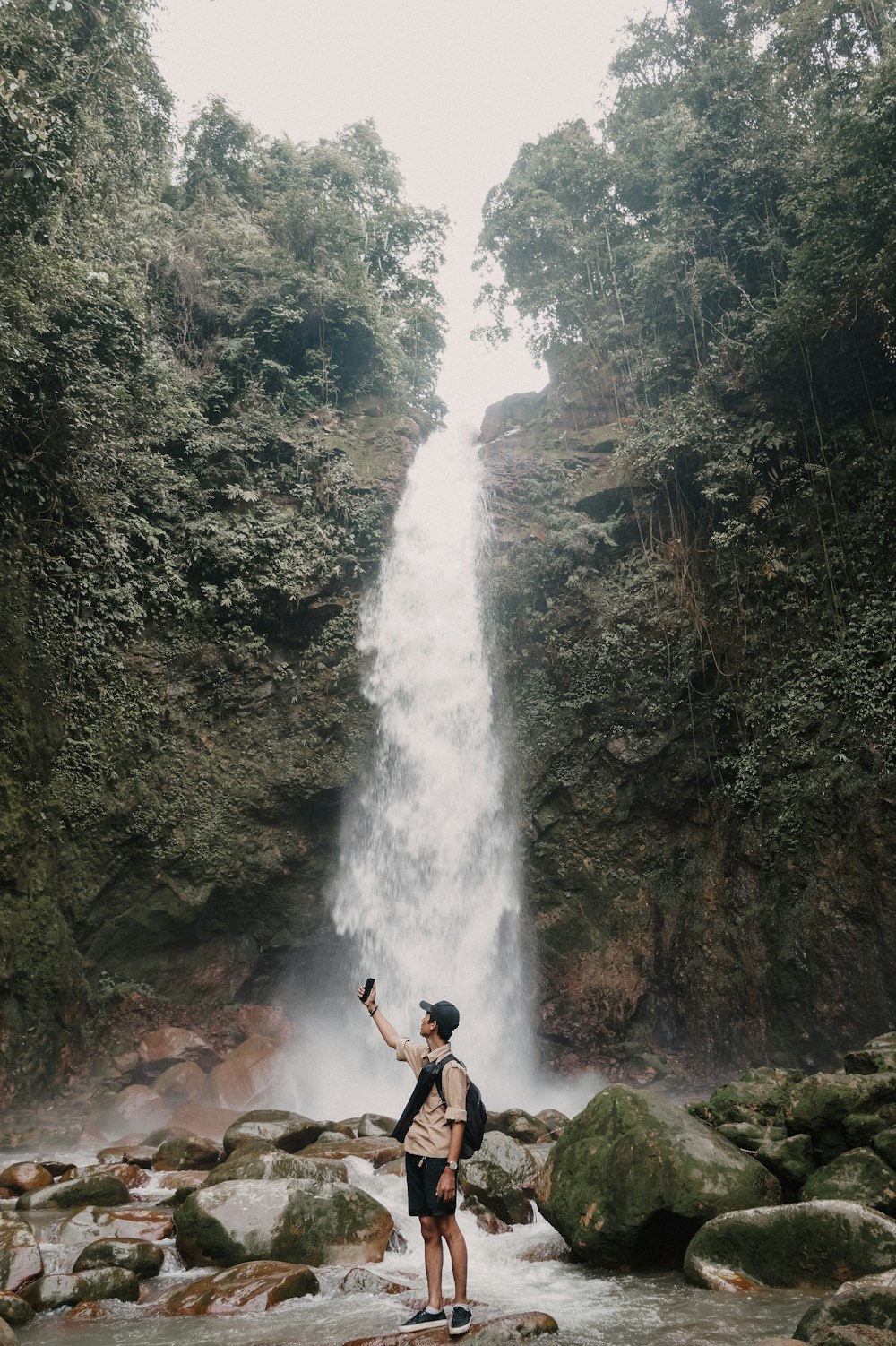 a man standing in front of a waterfall