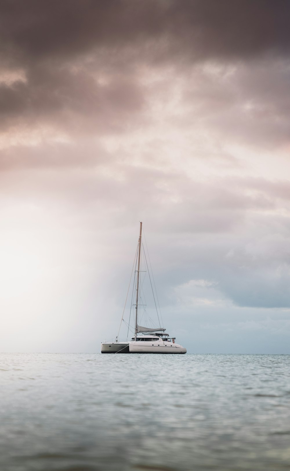 white sailboat on sea under white clouds during daytime