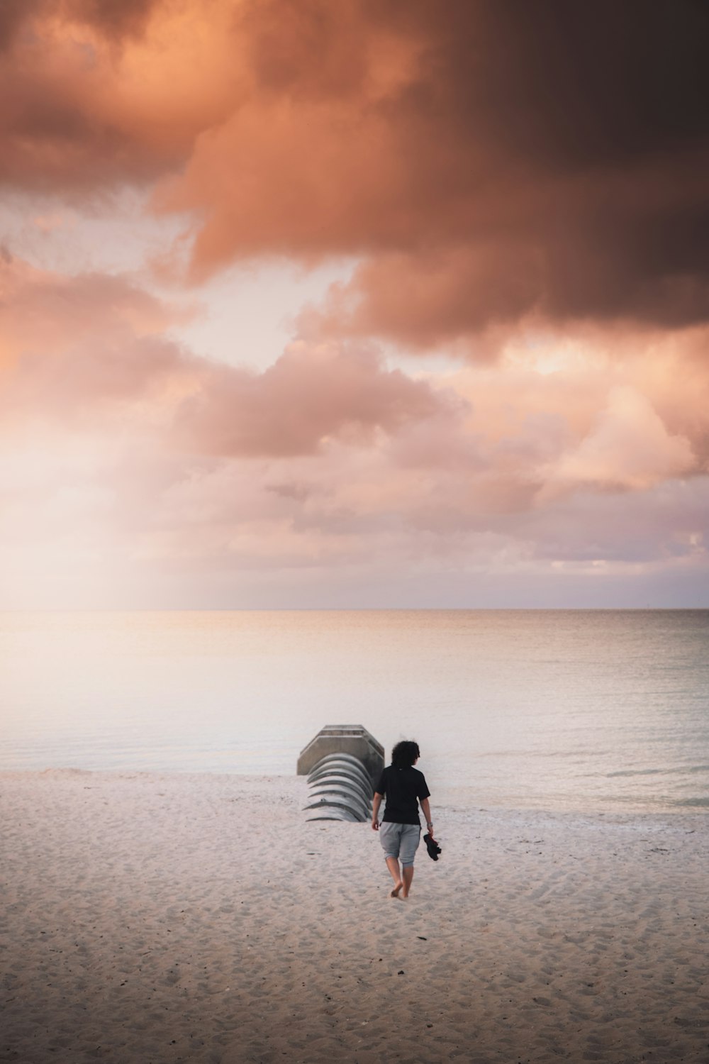 person in black jacket carrying white and black backpack walking on beach during daytime