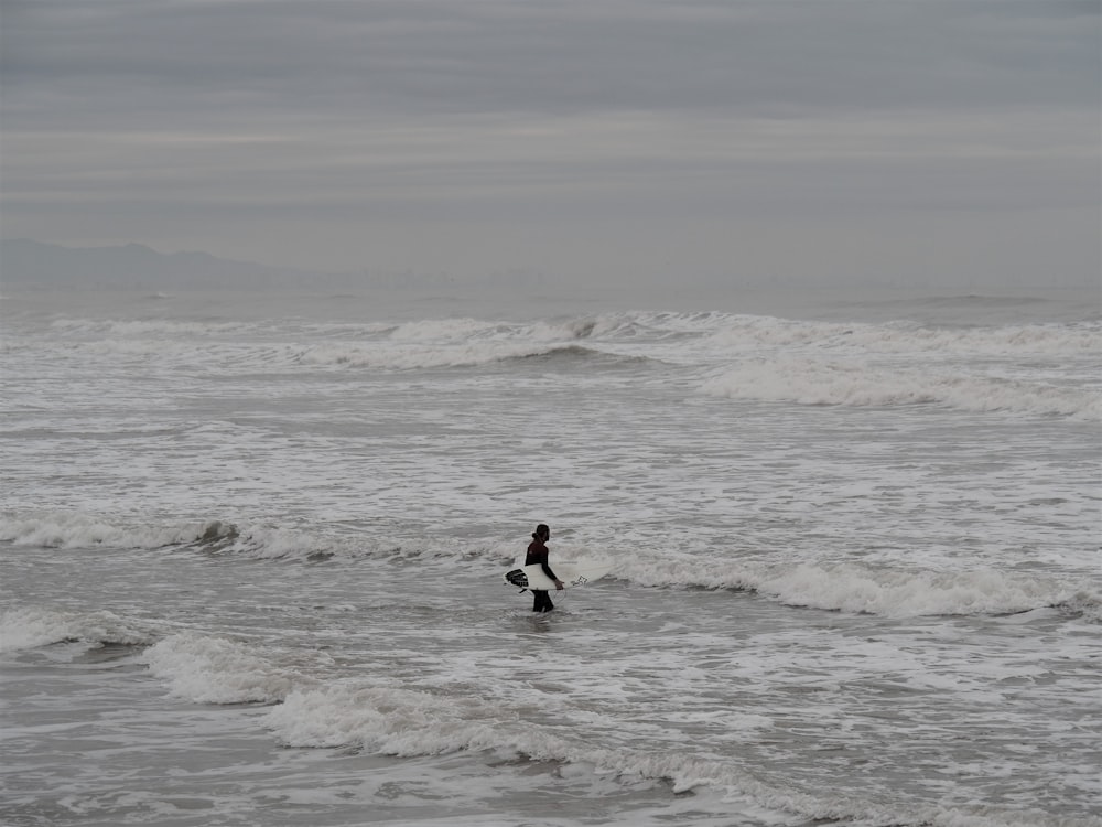 man in black wet suit surfing on sea waves during daytime