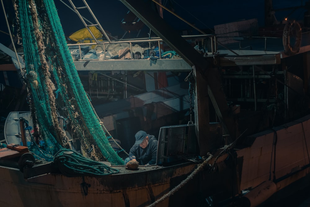 homem na camisa preta sentado no barco marrom durante o dia