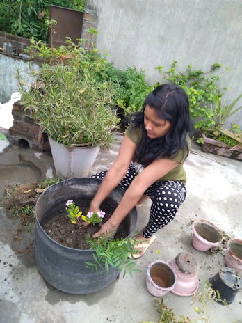 Close-up of hands planting fresh flowers amidst a hardscaped patio area with stone tiles.