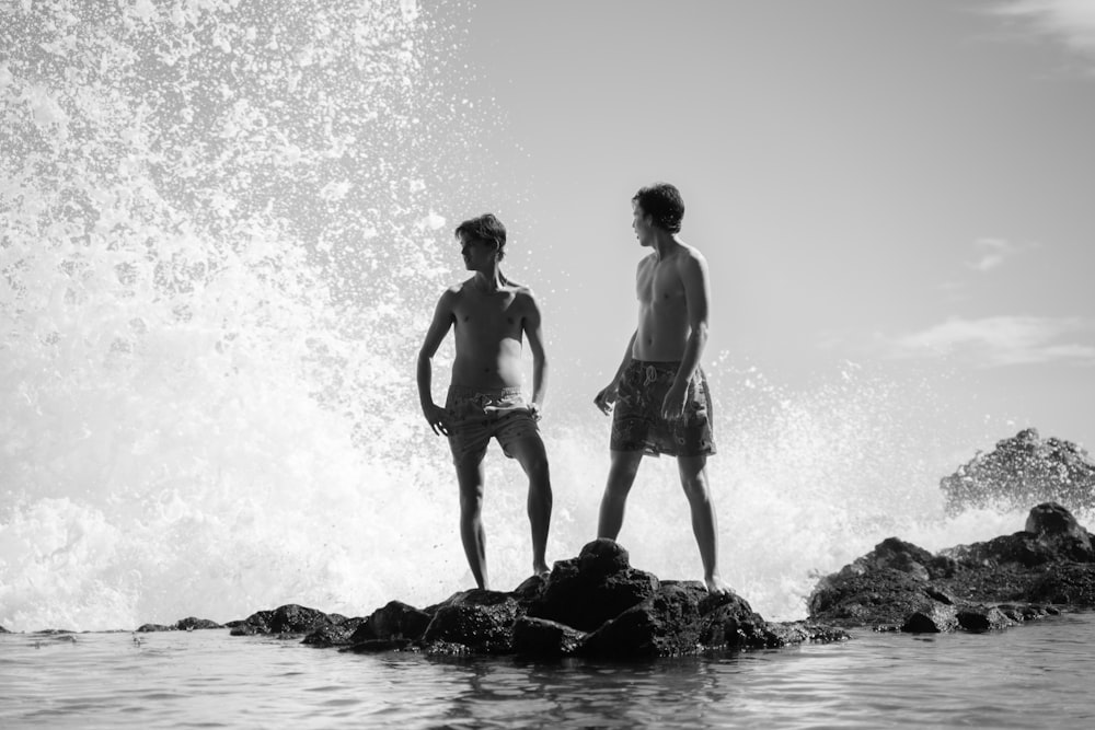 2 women standing on rock in grayscale photography