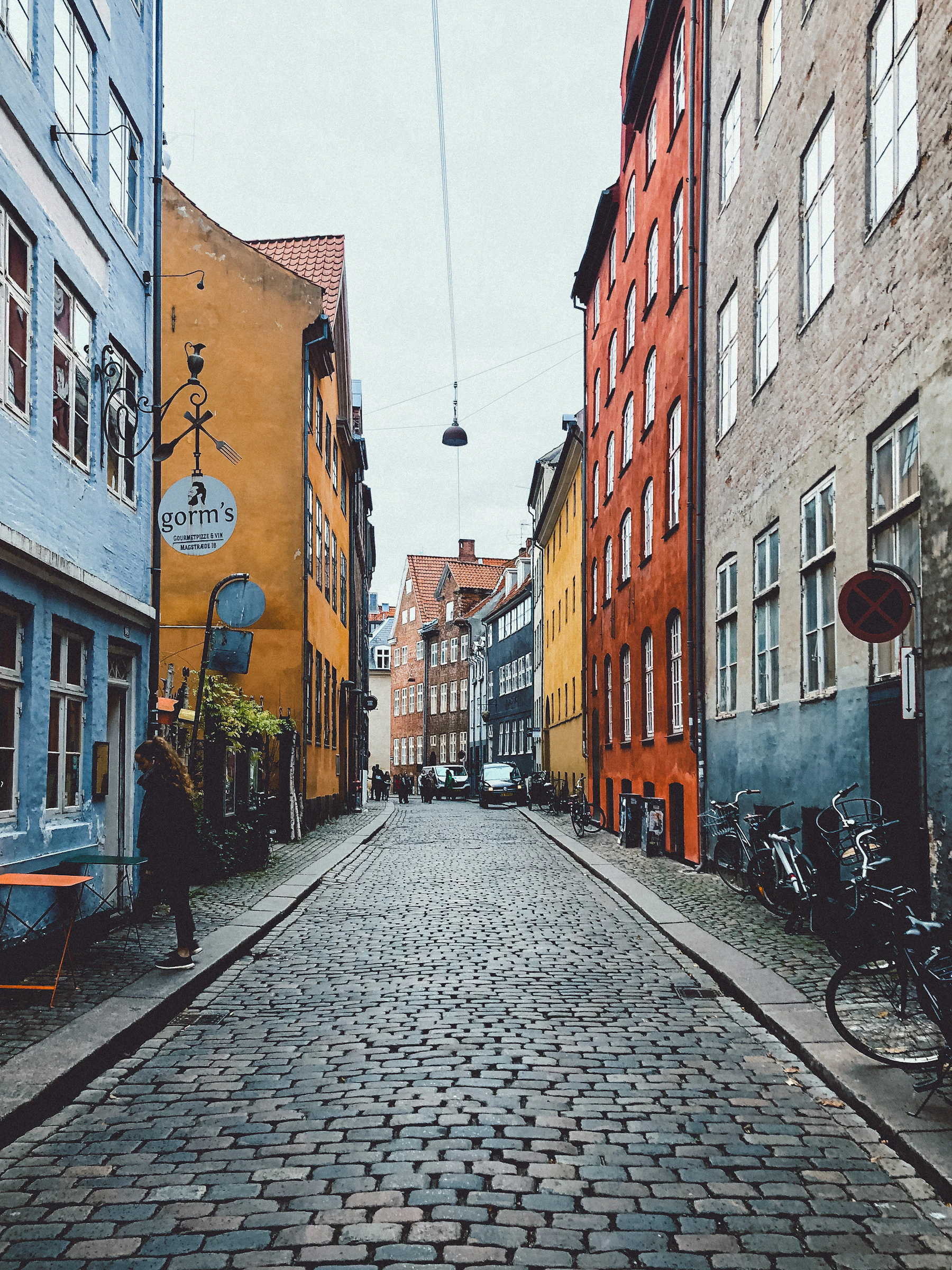 A bicycle stands beside a cobbled Copenhagen street lined with buildings.