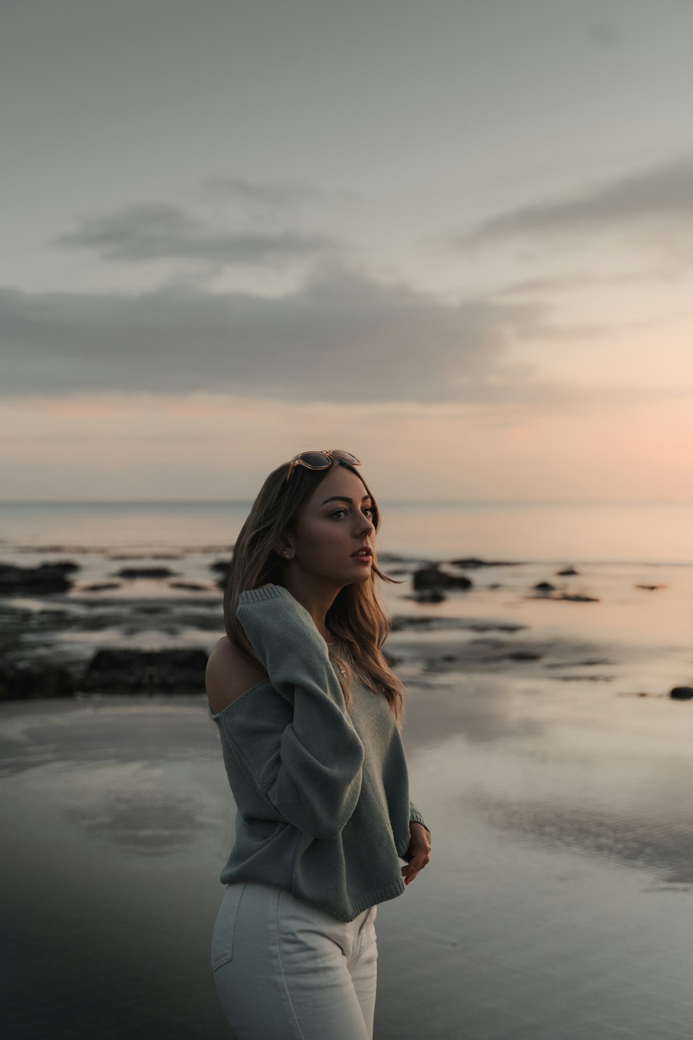 woman in white coat standing on beach during daytime