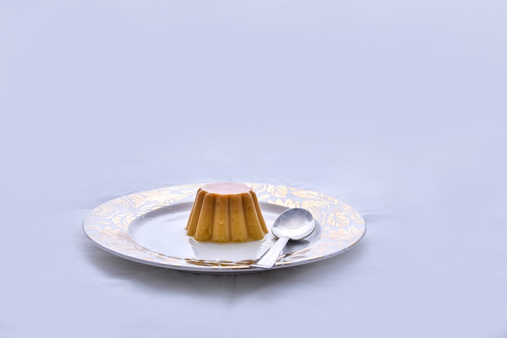 brown and white ceramic saucer with stainless steel spoon