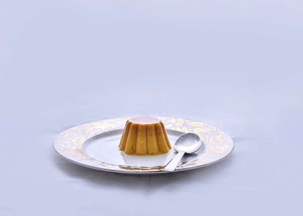 brown and white ceramic saucer with stainless steel spoon