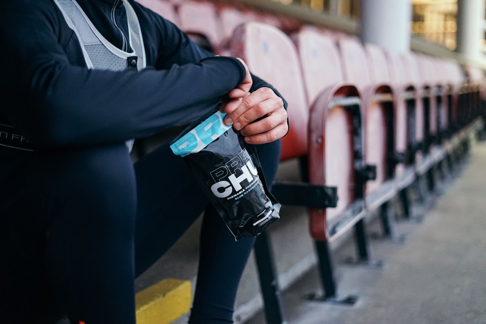 person in black jacket holding black and white plastic cup