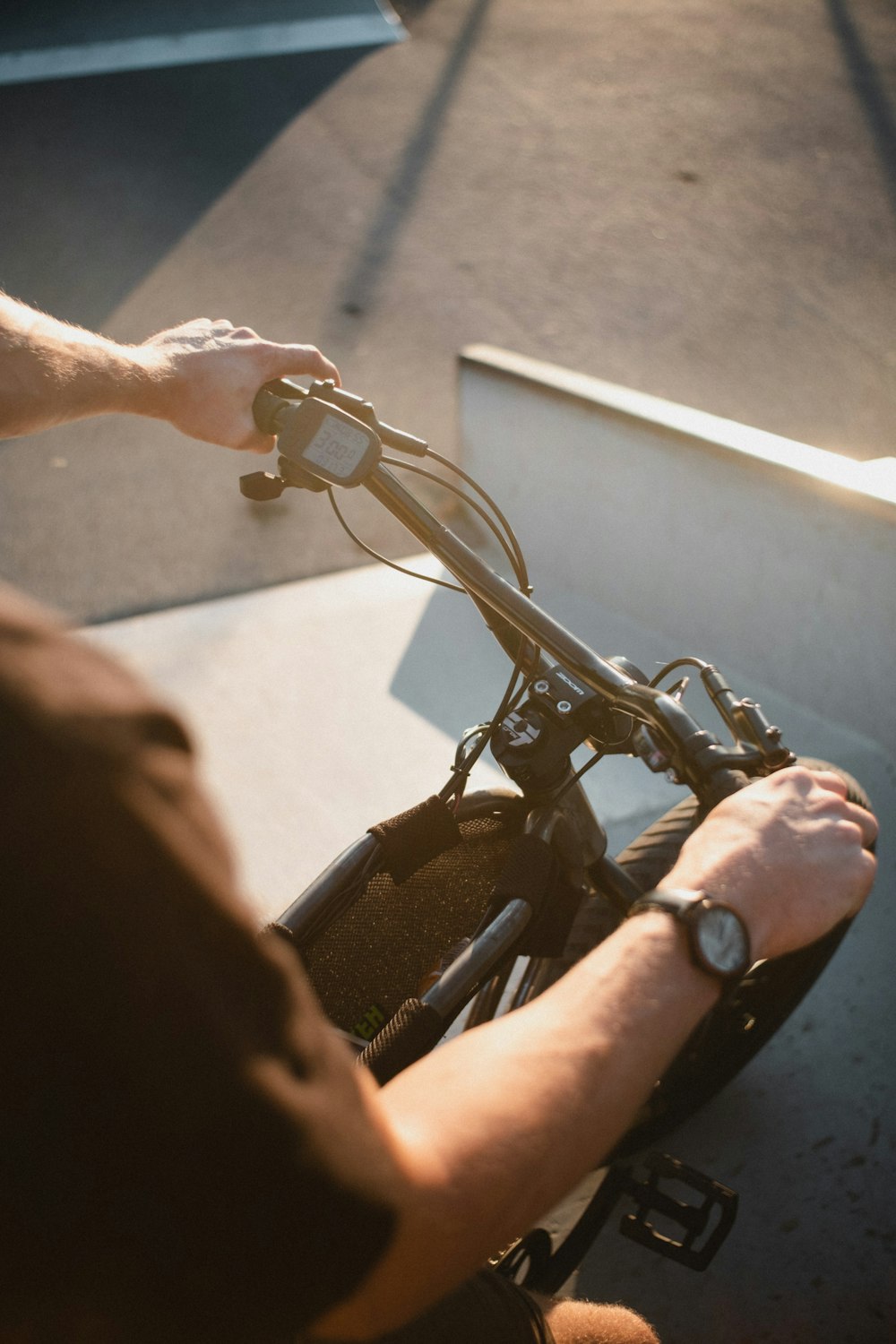 person wearing silver watch holding black bicycle handle bar