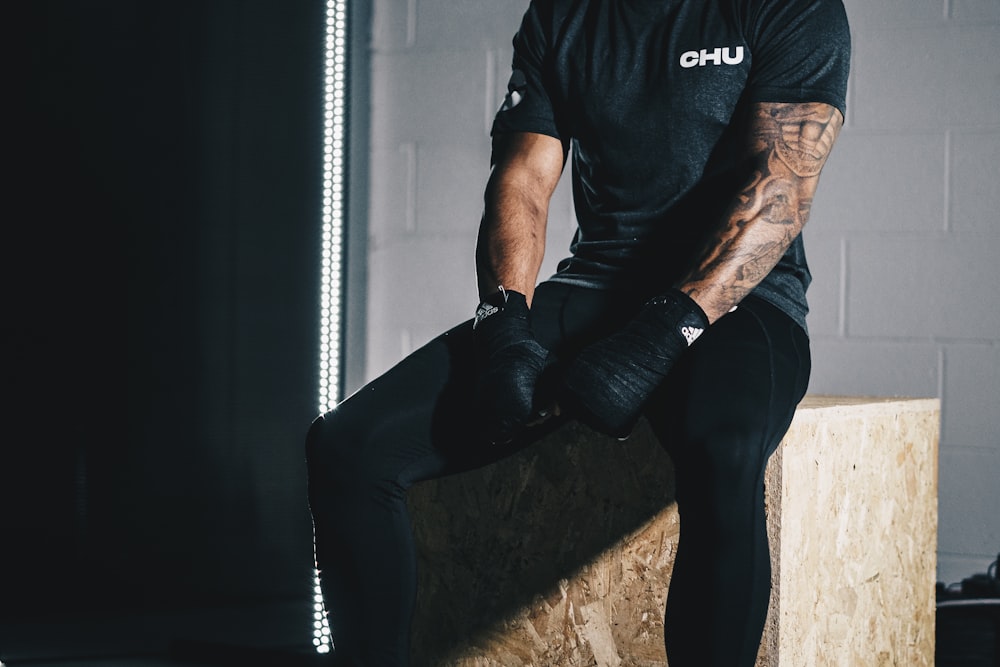 man in black crew neck t-shirt and black pants sitting on brown concrete stairs