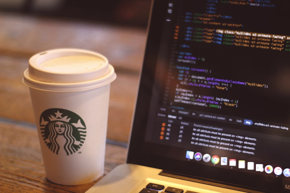 white starbucks cup beside black and silver laptop computer