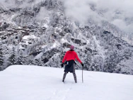 person in red jacket and black pants walking on snow covered ground