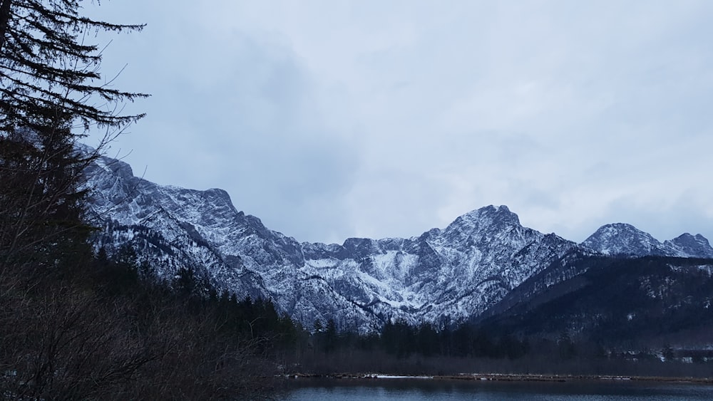 snow covered mountain near body of water during daytime