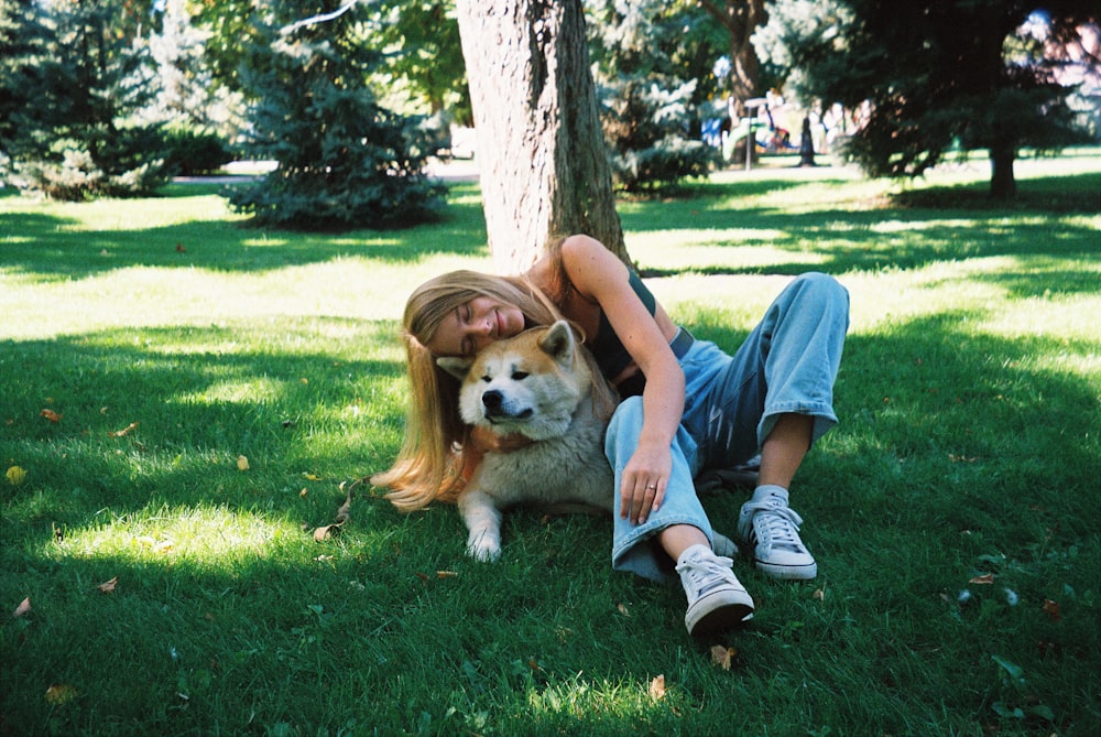 boy in blue t-shirt and blue denim shorts sitting on green grass field beside brown