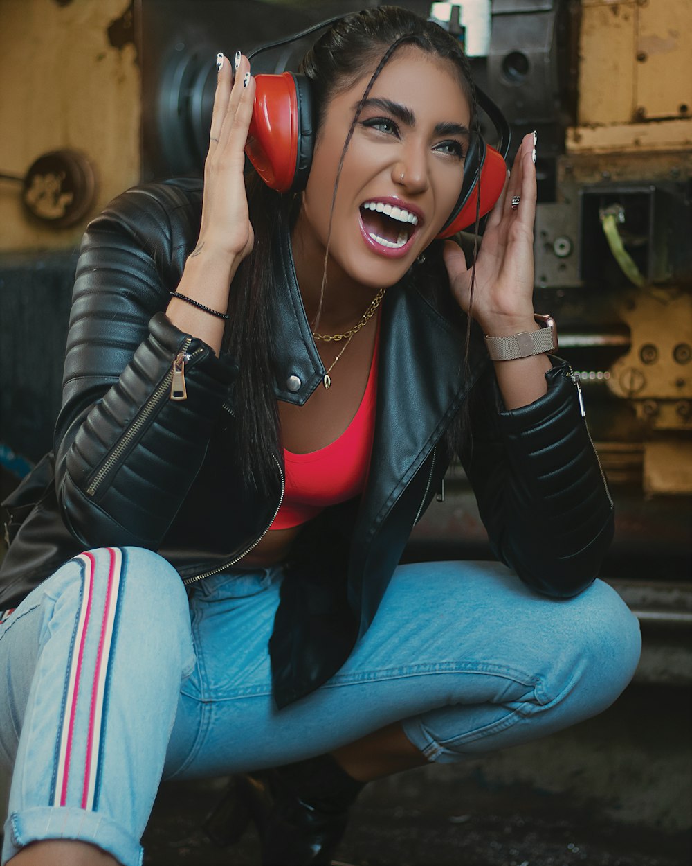 woman in black leather jacket and blue denim jeans wearing red headphones