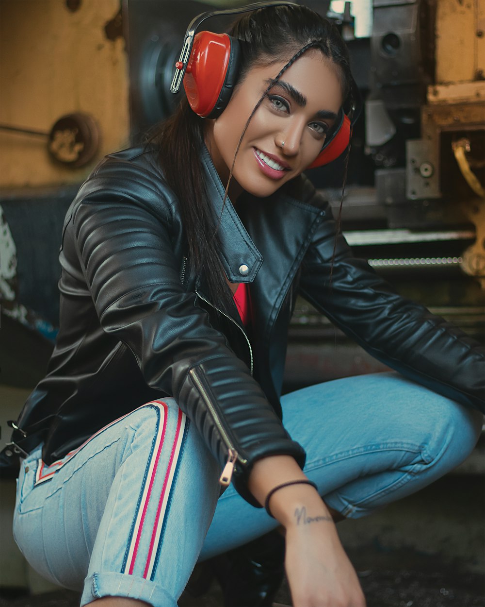 woman in black leather jacket and blue denim jeans wearing red and black headphones