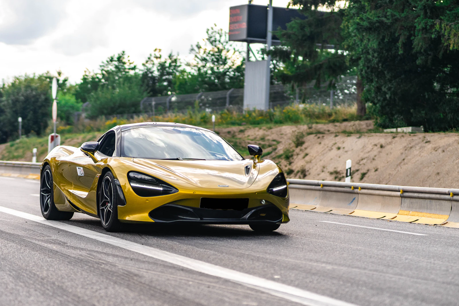 Gold McLaren 720S driving on an open road