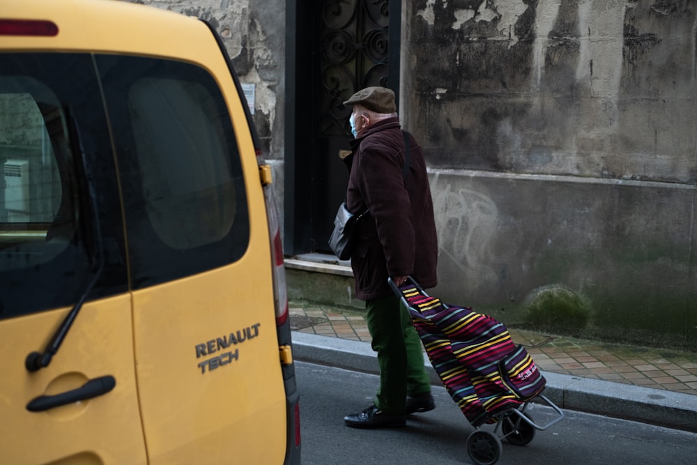 man in black jacket and black pants walking beside yellow bus during daytime