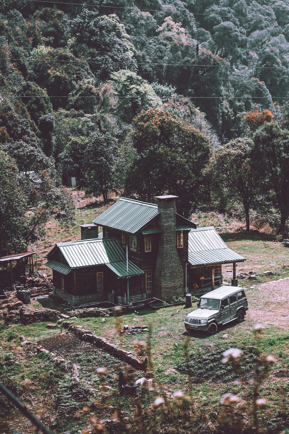 Auto nera parcheggiata accanto alla casa di legno verde e marrone durante il giorno