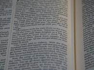 Close-up view of an open book showing text from a religious or historical scripture. The passage focuses on an instruction involving the behavior of men drinking water, emphasizing the separation based on how they drink.