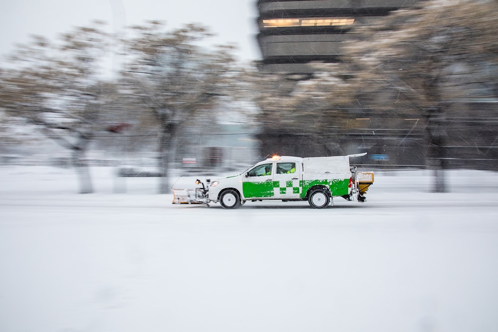 昼間の雪道の緑と白の車