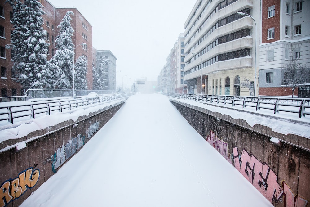 snow covered road between buildings during daytime